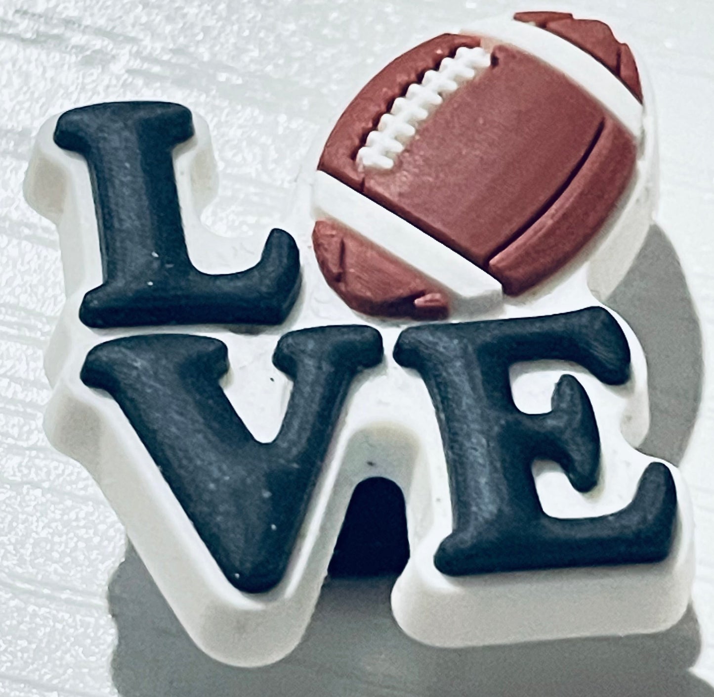 Decorative letter 'LOVE' with a football on a textured white background
