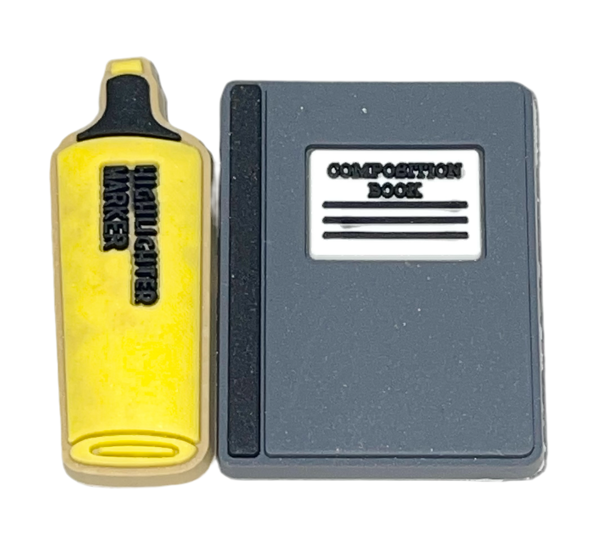 A shoe charm designed to look like a composition notebook with a highlighter shoe charm next to it.